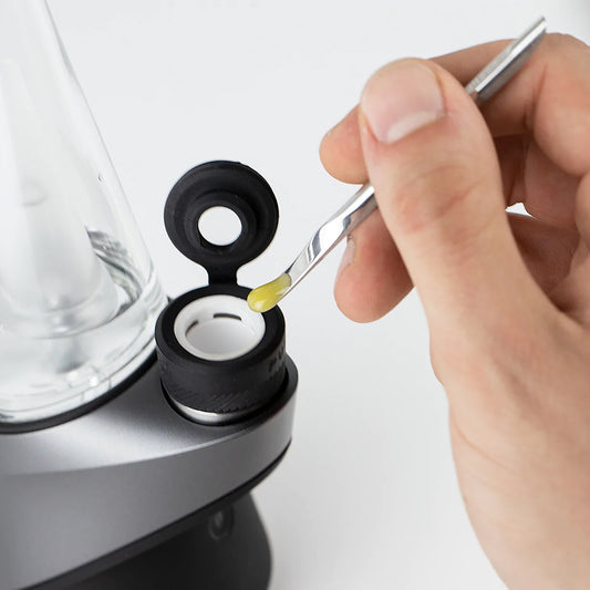 A hand adding wax into the Puffco Peak Pro chamber.